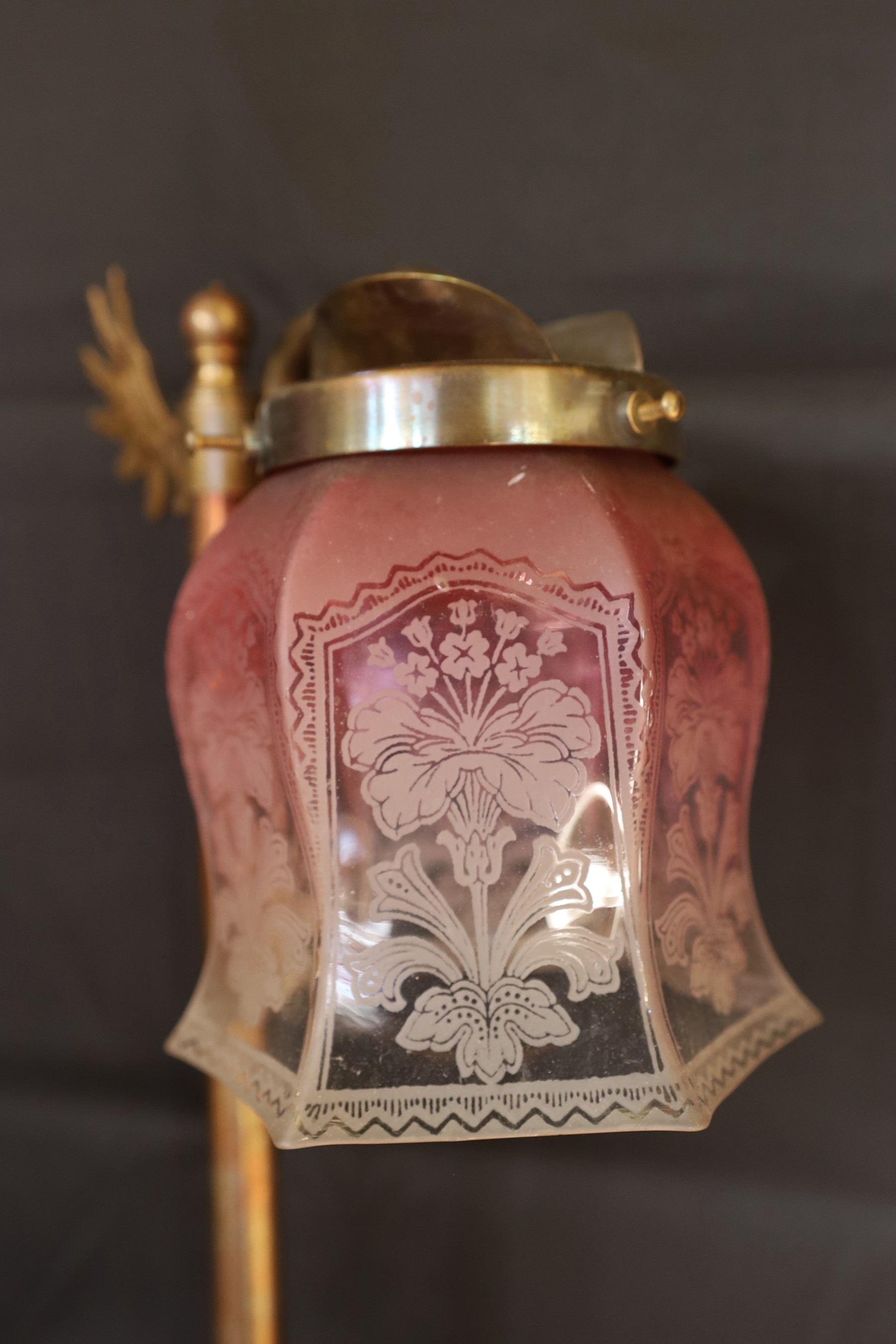 An Edwardian style bronze metal desk lamp with angel wing motif and cranberry tinted etched glass shade, height 49cm